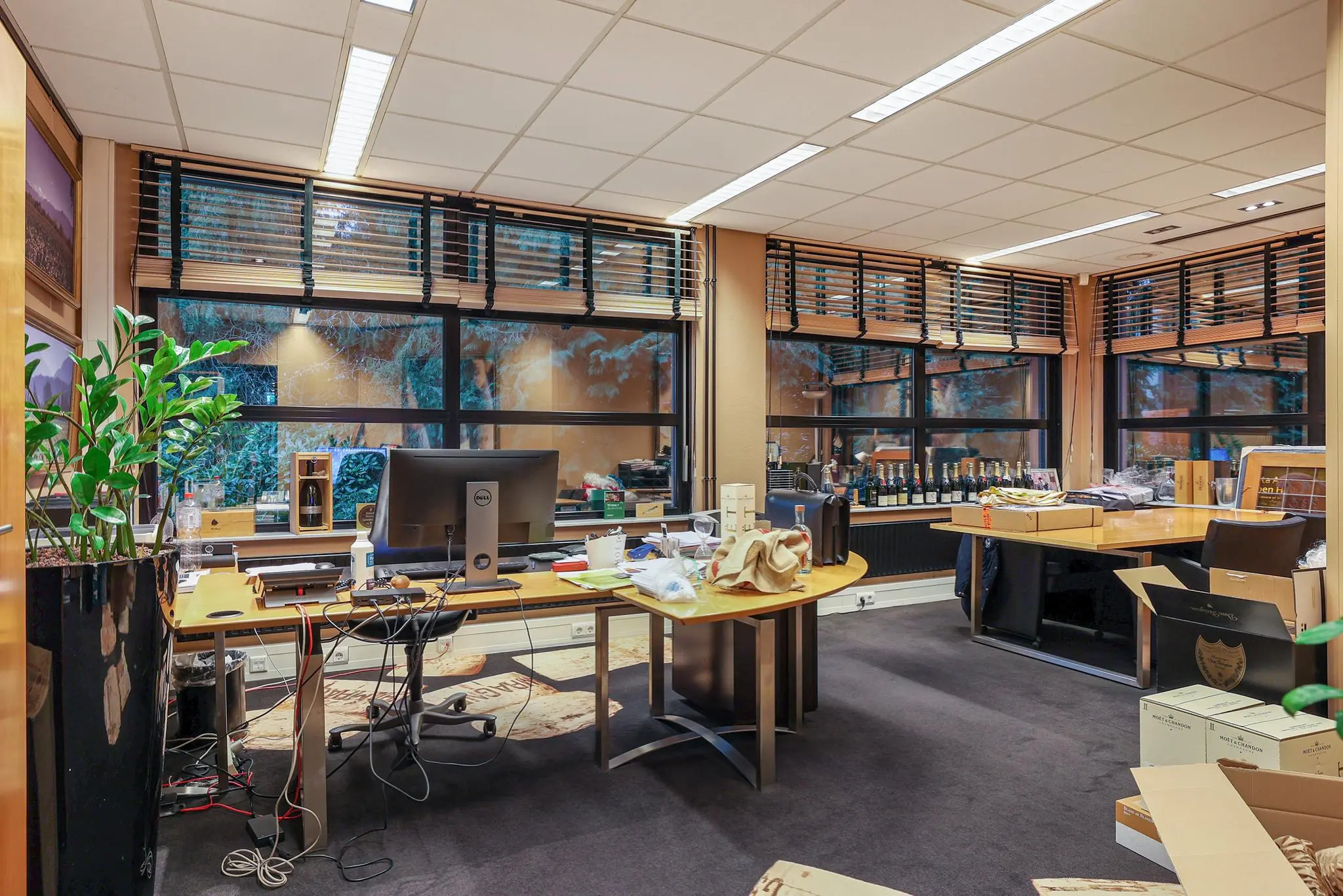 Modern kantoor aan de Oude Utrechtseweg met bureaus, computers, wijnflessen en verhuisdozen.